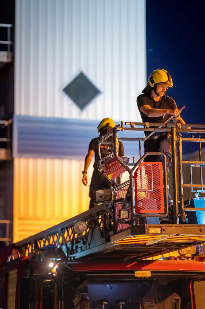 Deux pompiers s'activent sur la nacelle d'une grande échelle de nuit, par Vincent Delesvaux, photographe et vidéaste à Lyon.