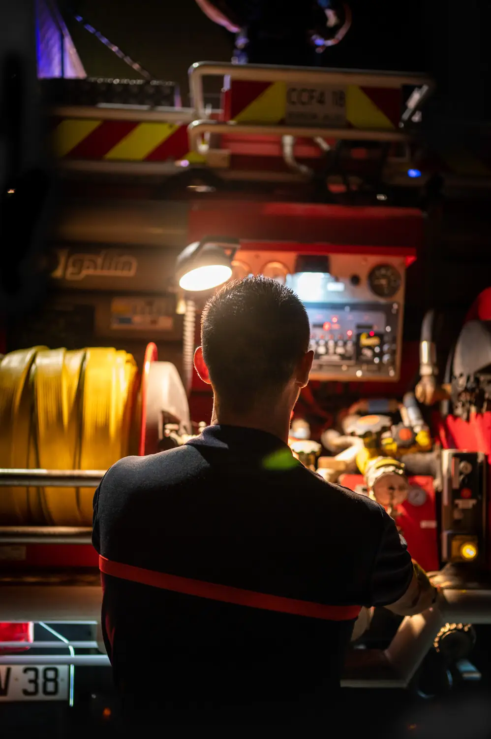 Un sapeur-pompier de dos face au tableau de bord lumineux d'un camion rouge, par Vincent Delesvaux, photographe et vidéaste à Lyon.
