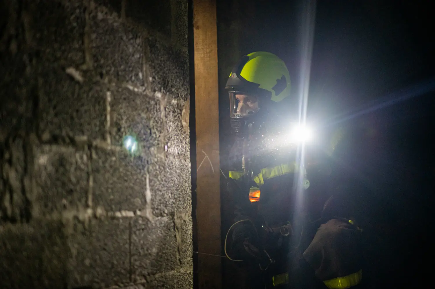Un pompier équipé d'un masque progresse dans le noir éclairé par sa lampe, par Vincent Delesvaux, photographe et vidéaste à Lyon.