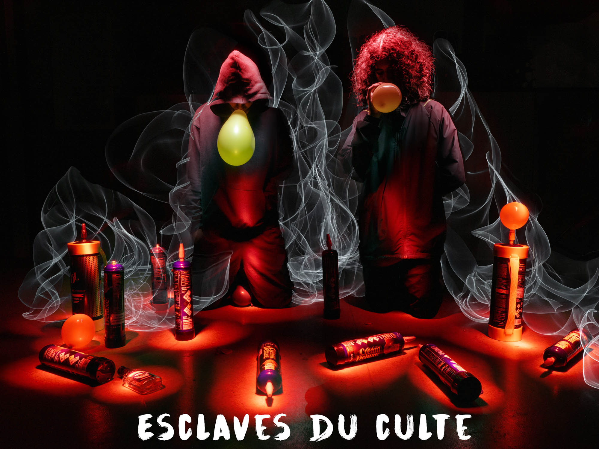 Deux adolescents à genoux inhalant des ballons dans une atmosphère de fumée rouge et de bonbonnes au sol, Vincent Delesvaux, photographe vidéaste